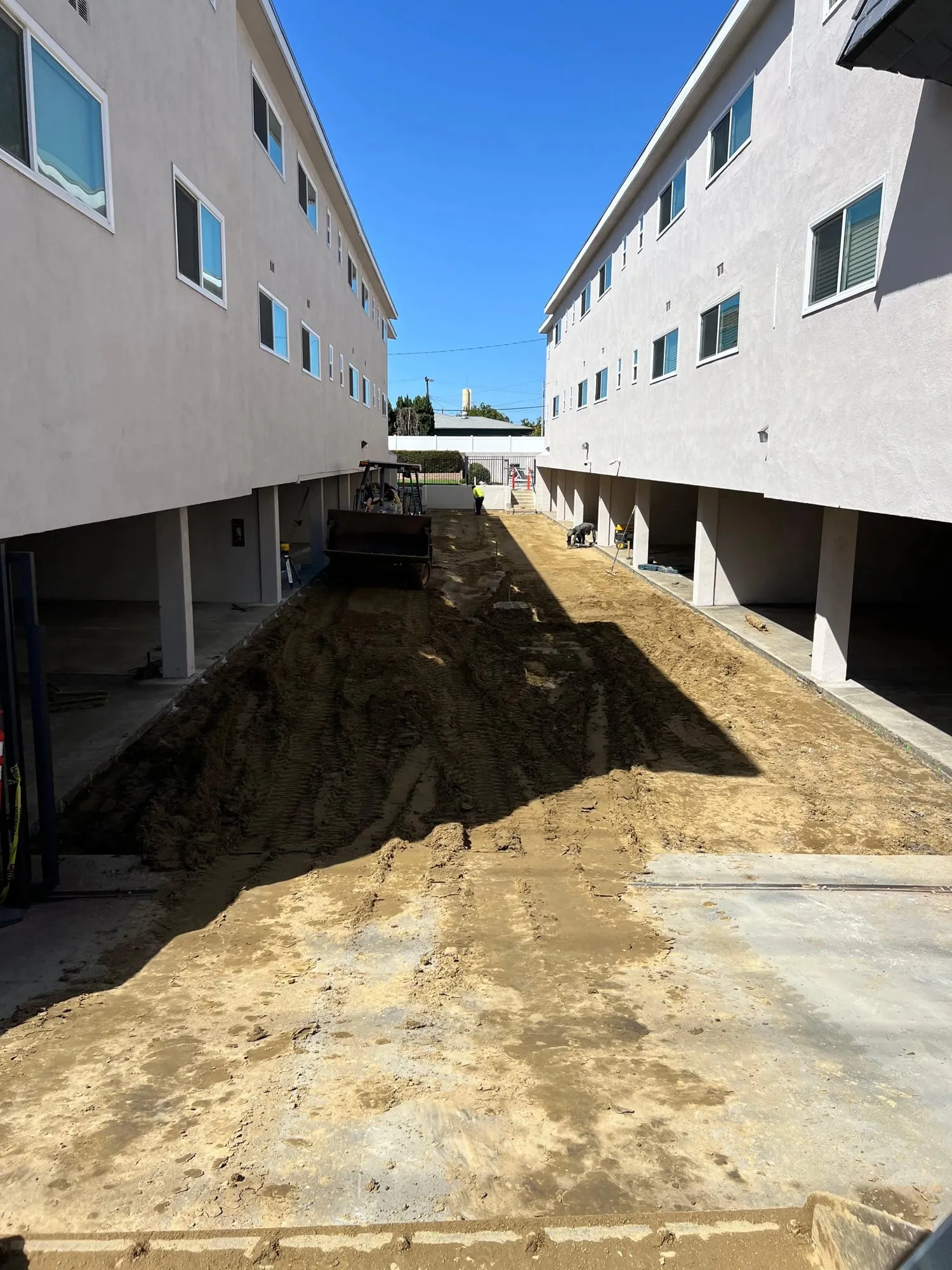 Graded dirt drive between two apartment buildings before the pour